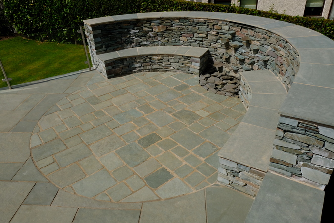 A raised platform was constructed to tackled the sloping garden. Within the structure was a seating area with an integrated water feature, built using Lakeland slate. Planting beds were incorporated into the raised structure to give year round colour.