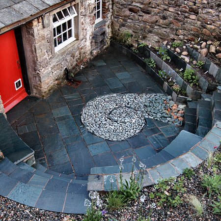 Sunken courtyard in Honister slate with seating and new steps as well as a rill water feature for relaxing after a hard day at work.
